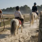 Balade a cheval Arcachon : cavaliers et poneys sur chemin sablonneux près des pins